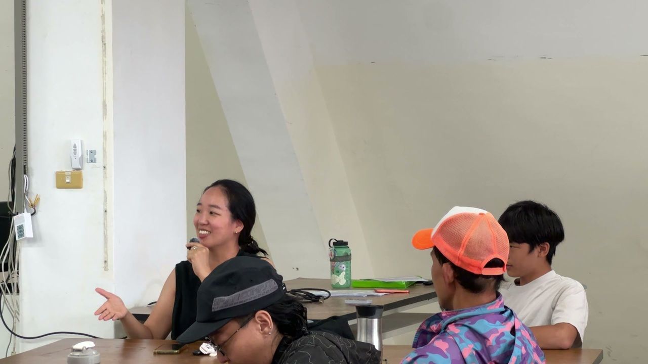 家長在課後分享時手持麥克風發言，其他參與者在一旁聆聽